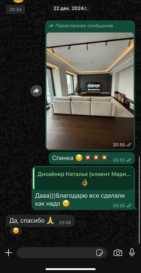 Светлый угловой диван вдоль стены в просторной гостиной с подсветкой потолка и новогодней ёлкой