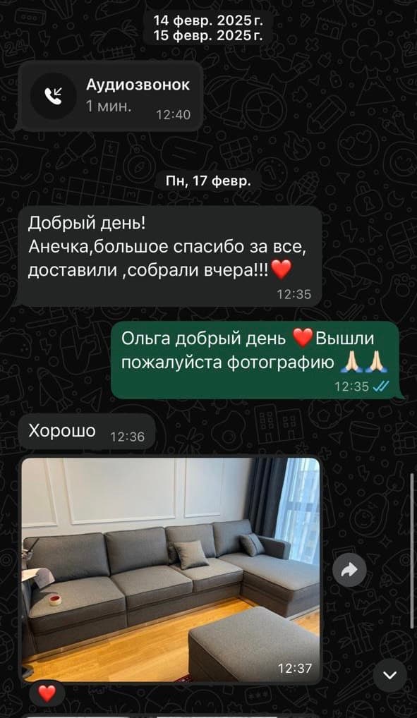 Серый диван с оттоманкой и пуфом у окна с тёмными шторами в светлой комнате с паркетом